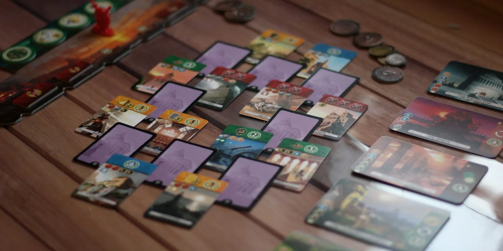 Illustrated game cards laid out in overlapping rows on a wooden table during a playtest session