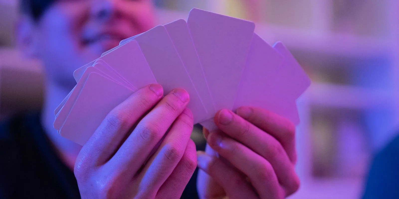 A player fanning out a hand of blank white cards waiting to be designed